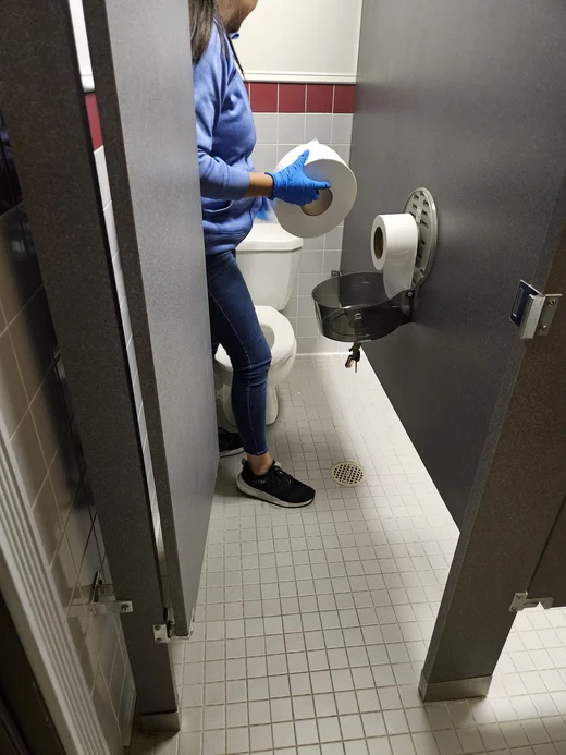 Cleaner wiping down a commercial restroom stall