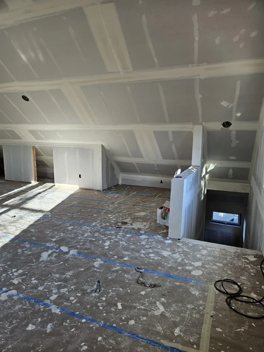 Attic room mid-remodel with new drywall and a protected floor