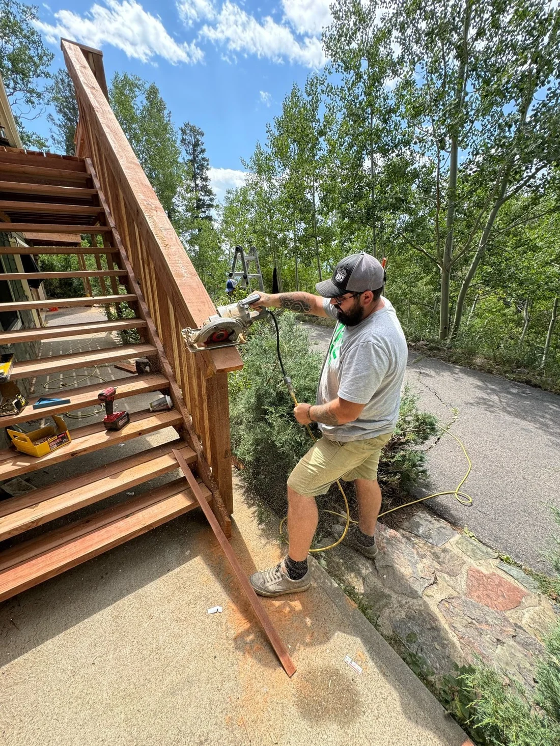 Handyman cutting a board while building a wooden staircase outdoors