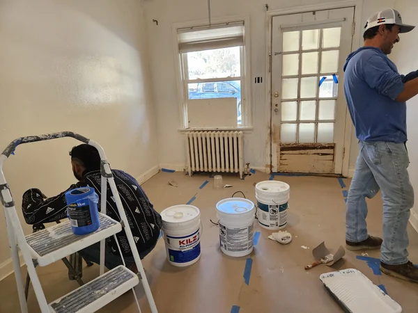 Room prepped for painting with buckets, a ladder and taped floors