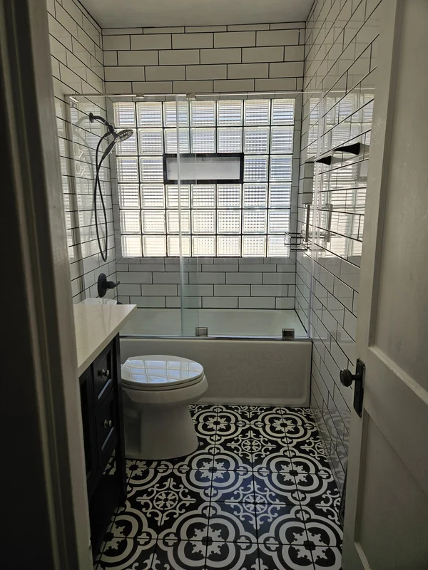 Remodeled bathroom with a subway tile shower and patterned floor tile