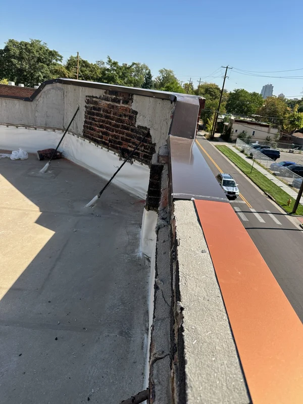 Flat roof with a damaged brick parapet before repair