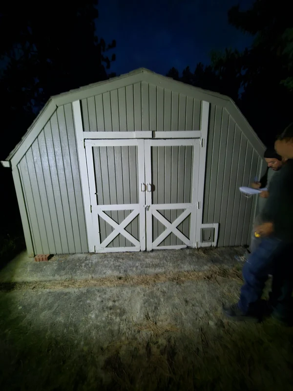 Newly built garden shed with white trim, photographed at night